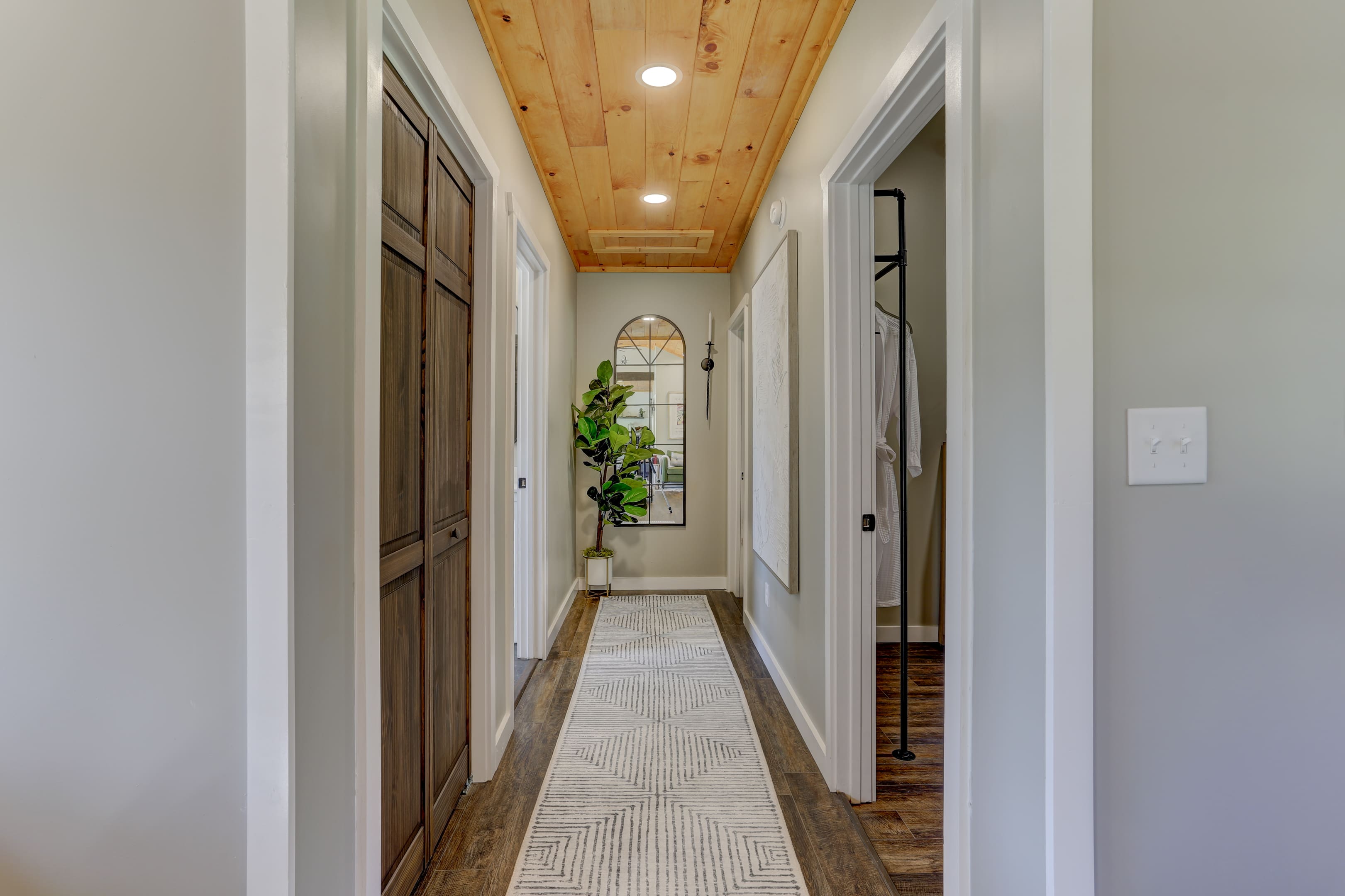 A hallway with two doors and a rug on the floor.