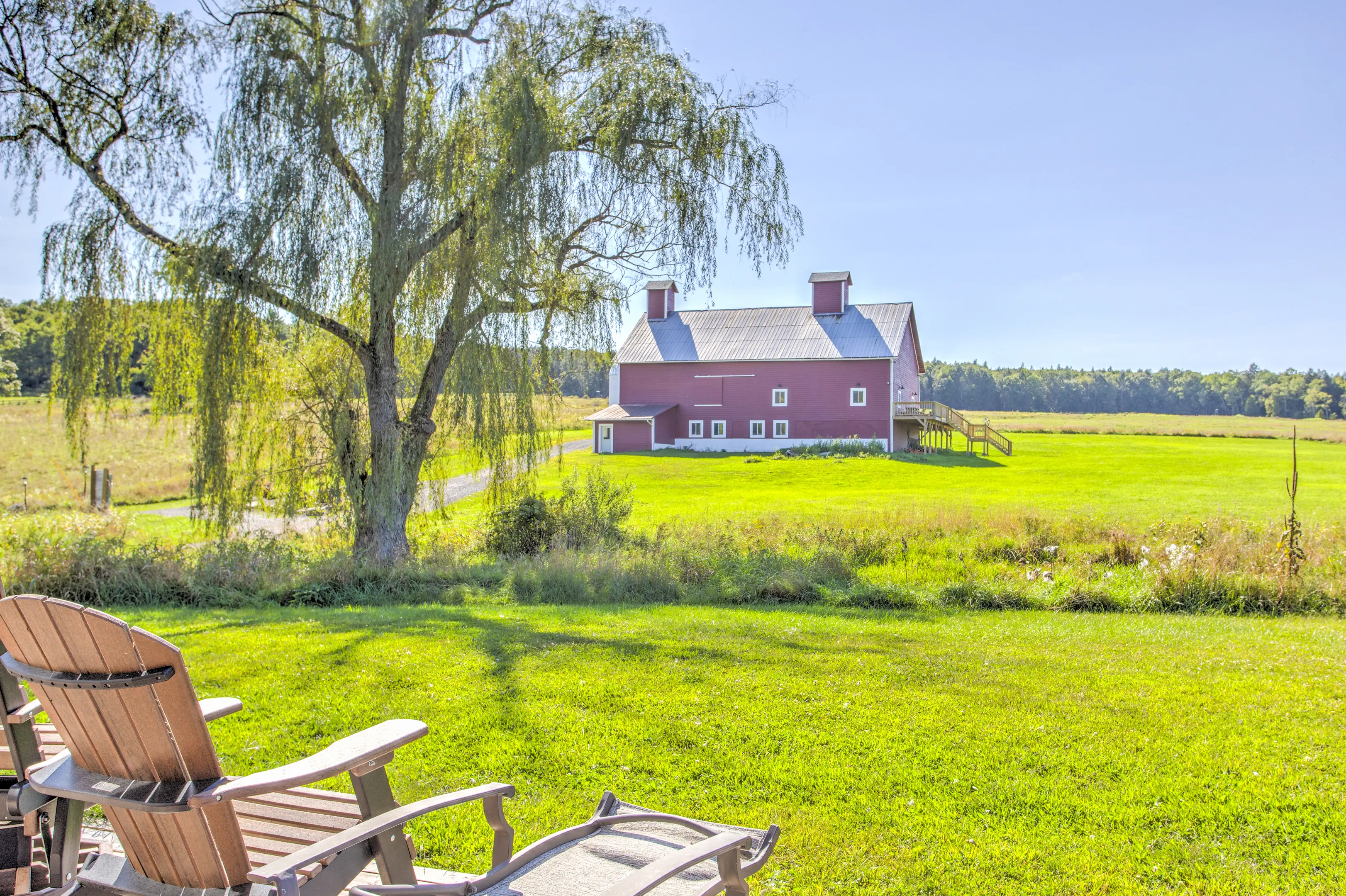 A red barn sitting in the middle of a green field.