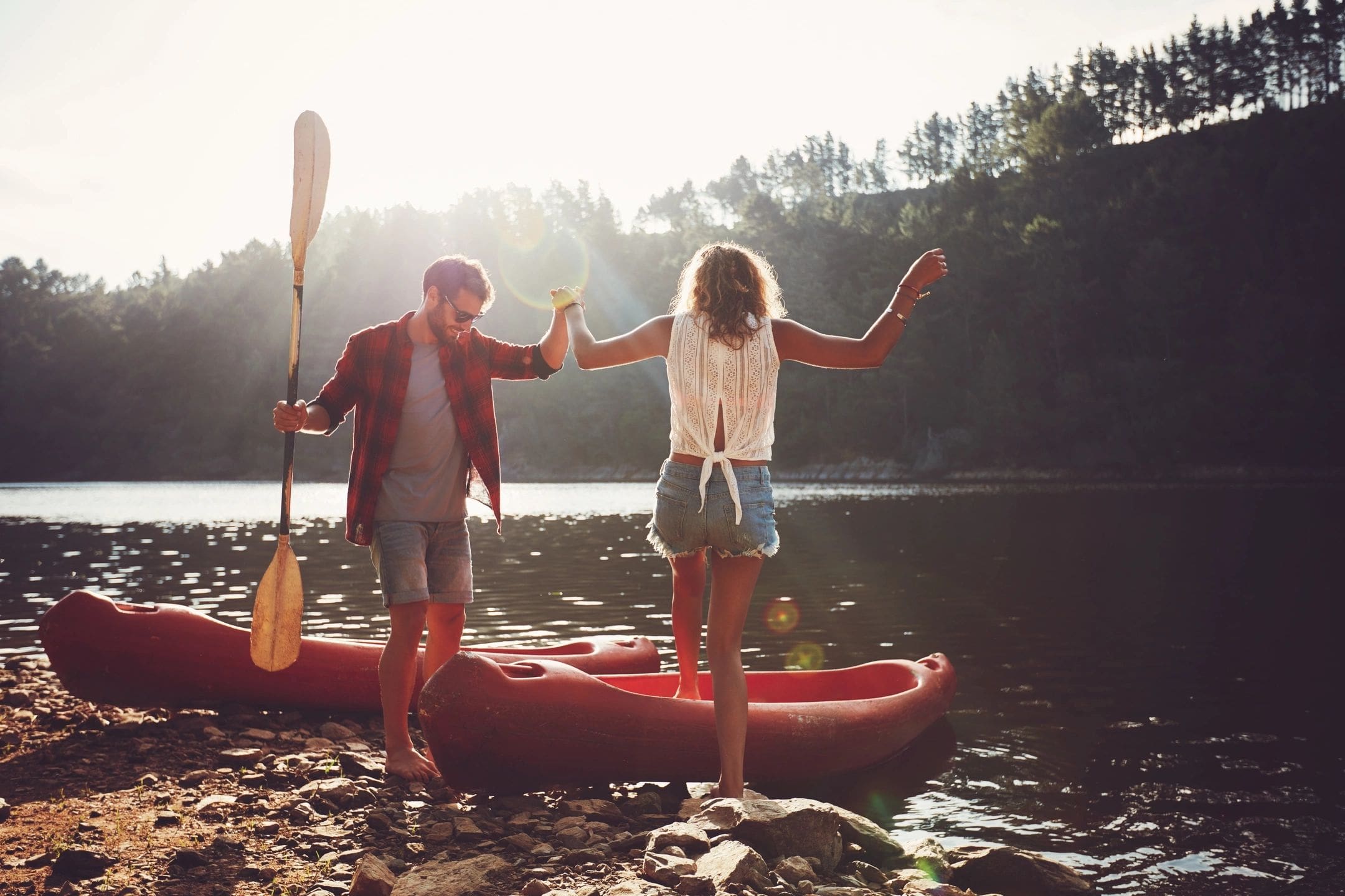 A man and woman standing on the shore of a lake.