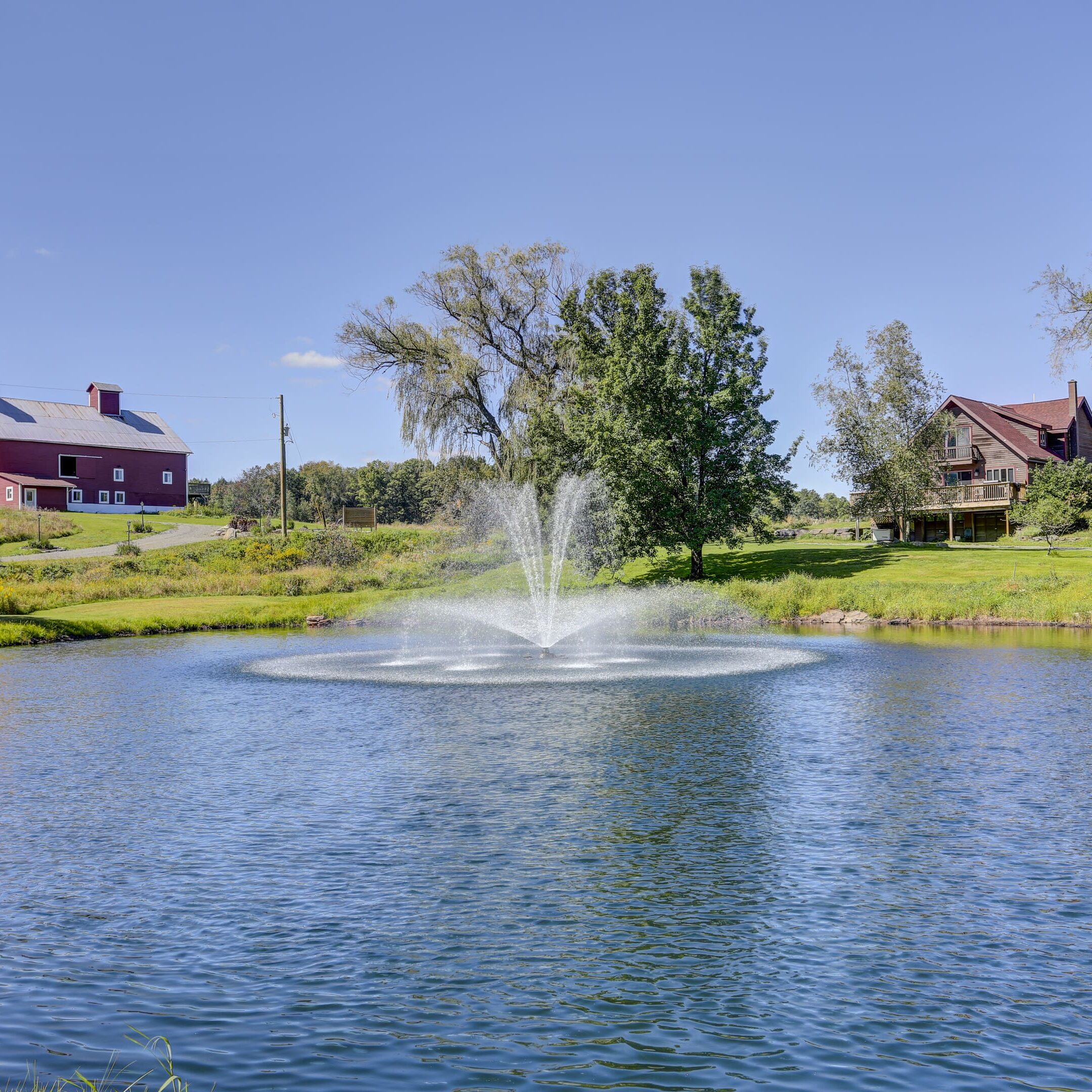 A pond with water fountain in the middle of it.