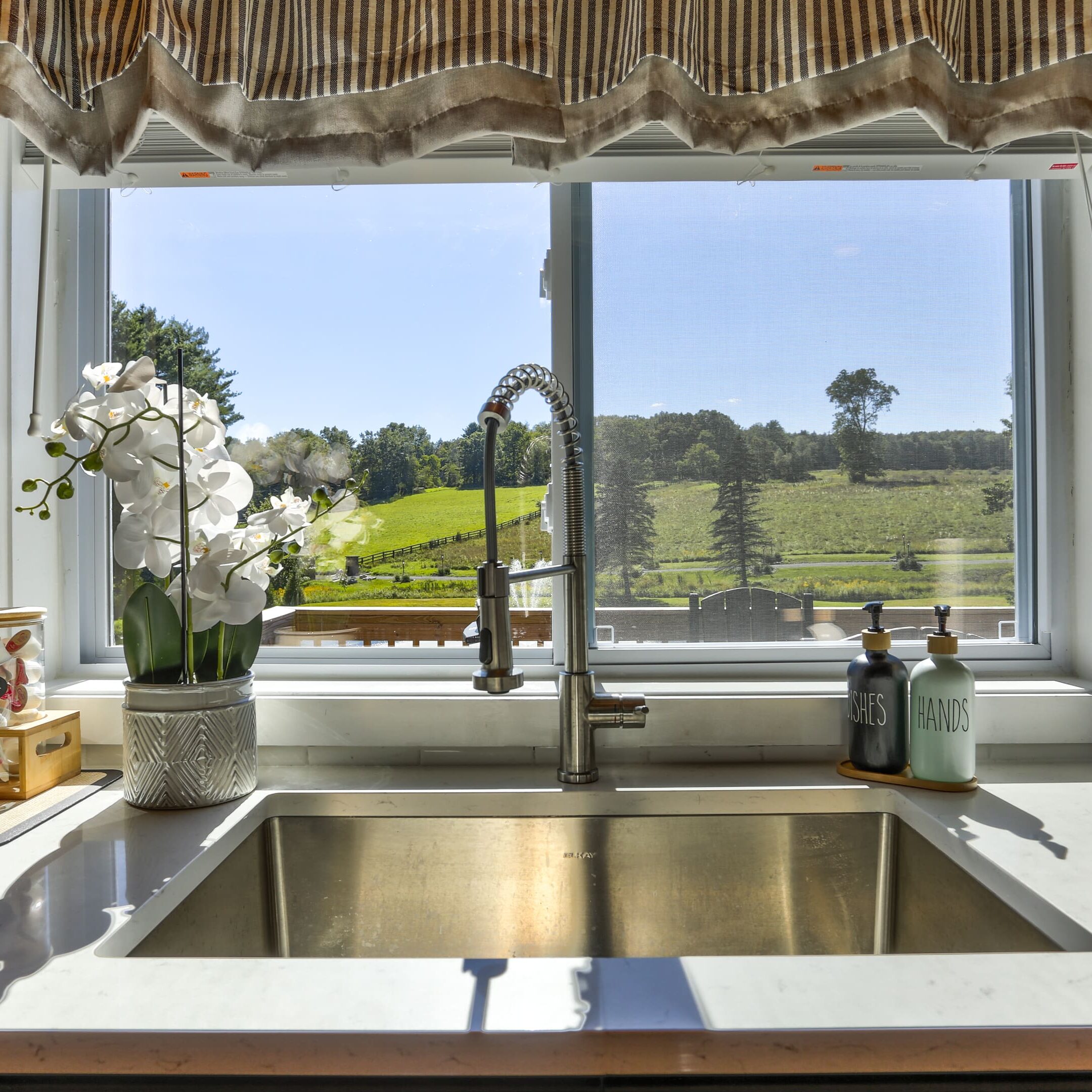 A kitchen sink with a view of the countryside.