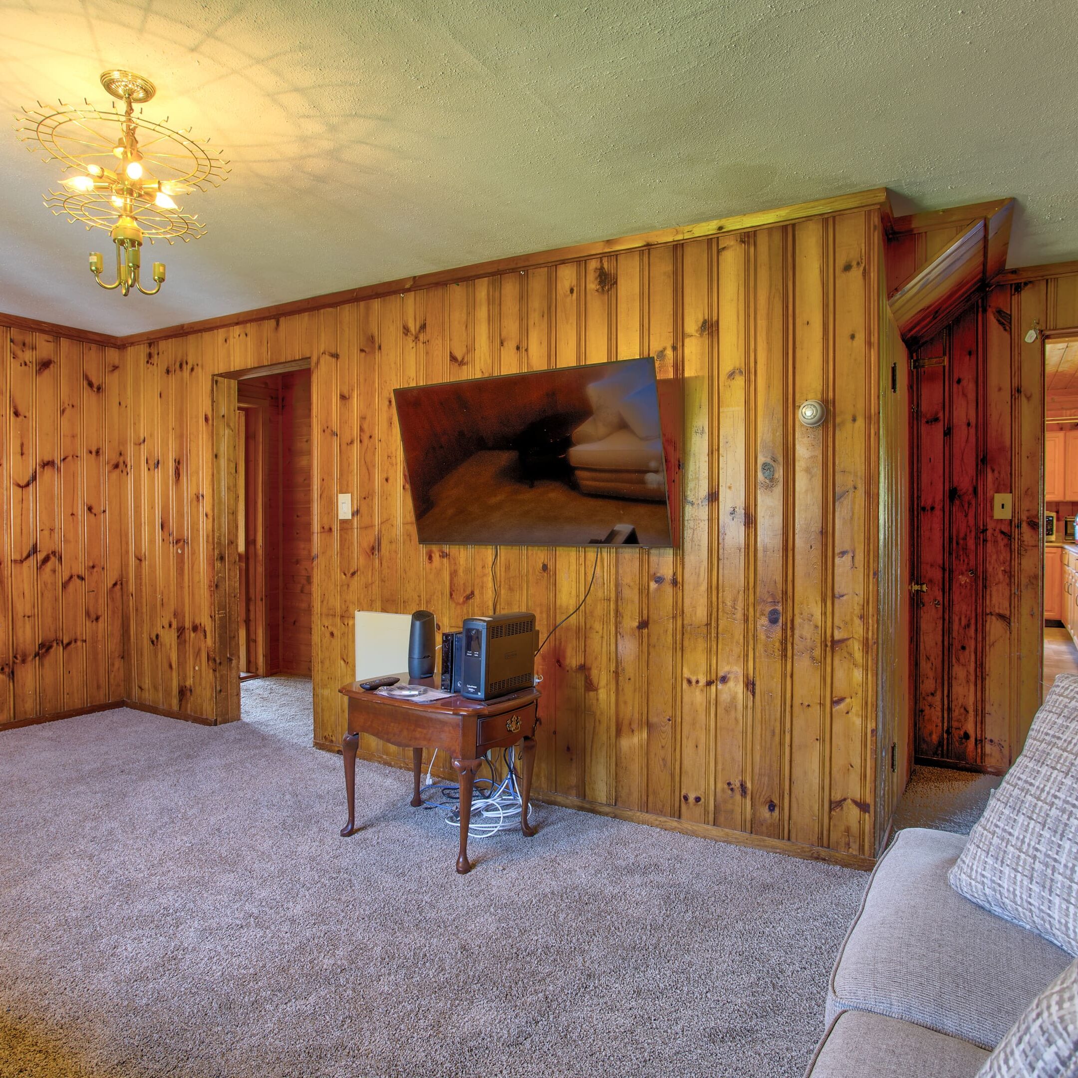 A living room with wood paneling and a television.