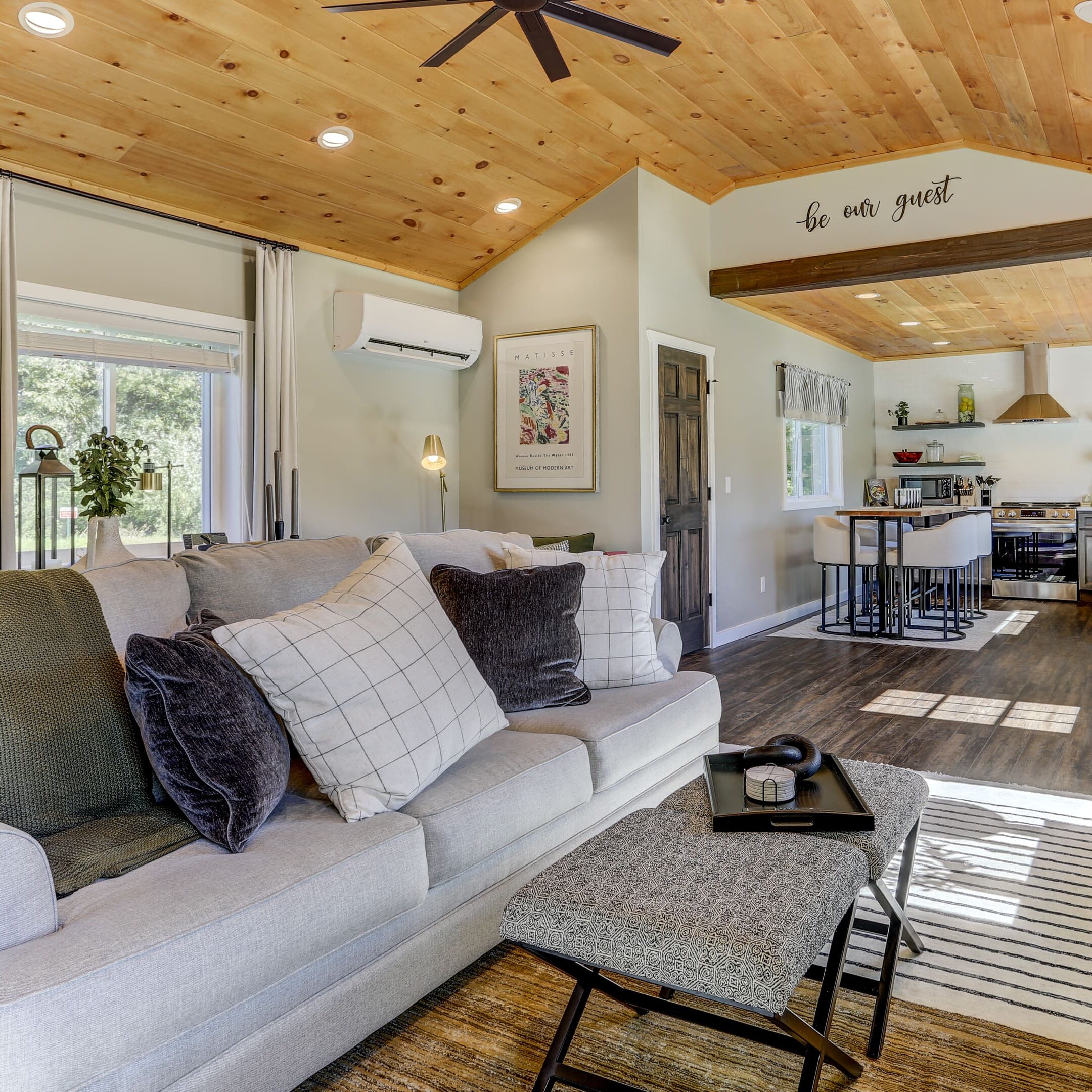 A living room with white couches and wooden ceiling.